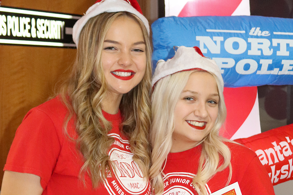 Two female students in Santa hats smiling