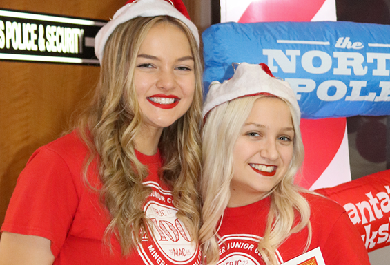 Two female students in Santa hats smiling